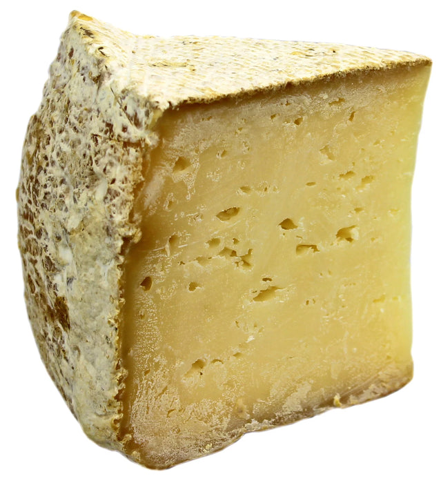 Sweet Grass Dairy | Thomasville Tomme cheese, a semi-soft, natural-rinded cheese with a subtle earthy flavor, showcased in a close-up of its textured surface.