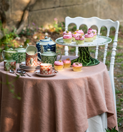 Vista Alegre | The Meaning Espresso Cup And Saucer on a blush-pink tablecloth beside a cake stand with cupcakes, part of an outdoor tea-party setup.