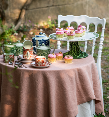 Vista Alegre | The Meaning Espresso Cup And Saucer on a blush-pink tablecloth beside a cake stand with cupcakes, part of an outdoor tea-party setup.