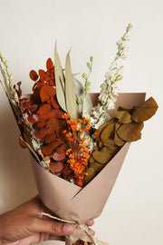 Idlewild Floral Co. - Harvest Dried Flower Mini Bouquet with eucalyptus, white spiky flowers, and orange blossoms wrapped in tan paper, tied with twine.