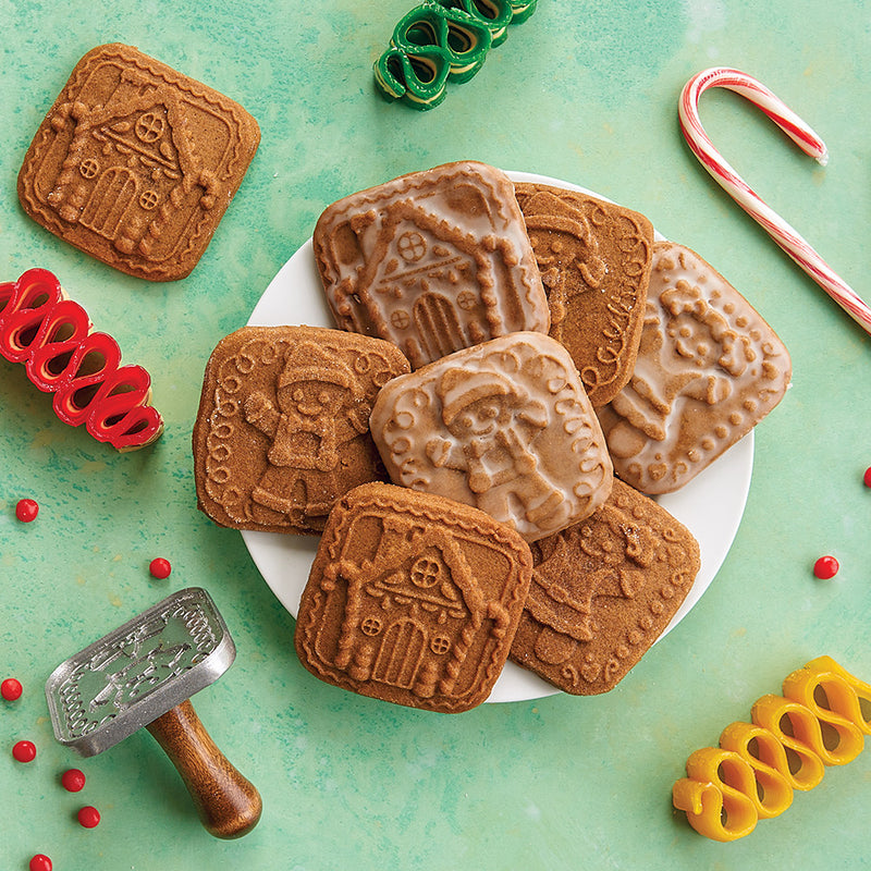 Nordic Ware | Gingerbread cookie stamps create holiday-themed cookies, featuring intricate gingerbread designs on a plate of cookies and candy.