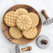Nordic Ware | Heirloom Cookie Stamps on a plate with cookies, showcasing intricate flower, scallop, and diamond patterns for crafting decorative baked goods.