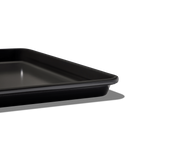 Great Jones | Little Sheet - Pepper: A close-up of a compact, rectangular black baking tray with a nonstick surface, perfect for small-portion baking or reheating.