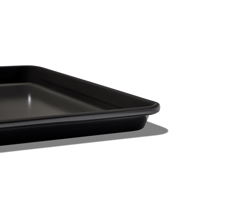 Great Jones | Little Sheet - Pepper: A close-up of a compact, rectangular black baking tray with a nonstick surface, perfect for small-portion baking or reheating.