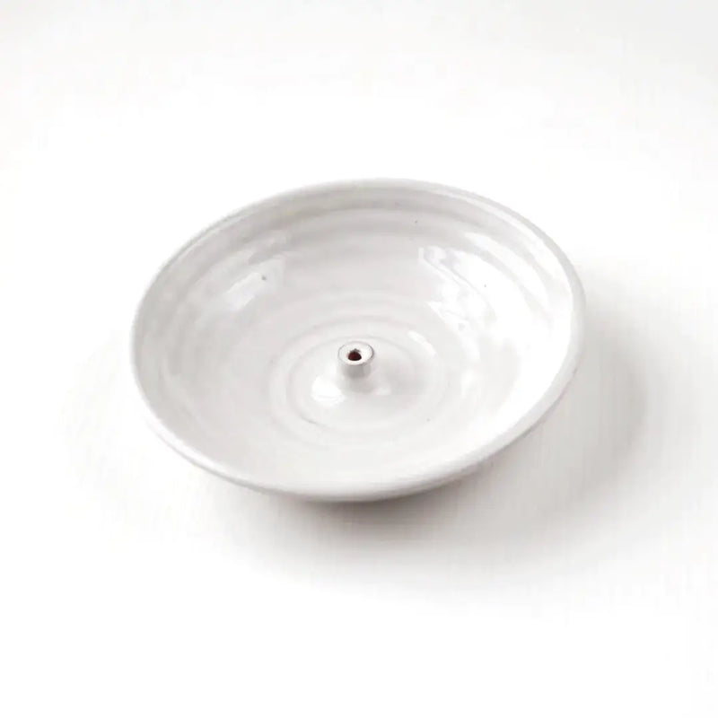 Gravesco Pottery Incense Burner: A round white ceramic dish with a central peg to hold incense sticks, perfect for catching ash and protecting surfaces.