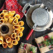 Nordic Ware | Norwegian Krumkake and Pizzelle Iron with a red handle, includes a two-sided Krumkake press, cooking base, and wooden rolling cone for traditional cookie making.