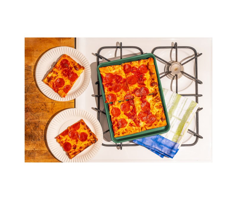 Great Jones | Little Sheet - Pepper shown with a pepperoni pizza, highlighting its compact size and nonstick surface for easy baking or reheating.
