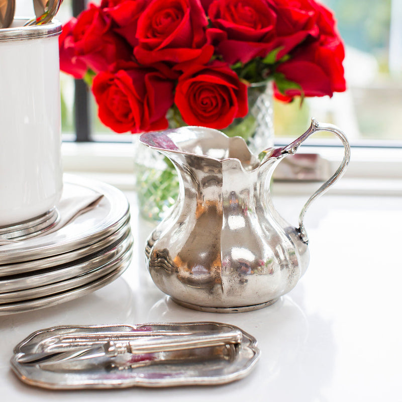 Arte Italica & Crown Linen Designs' vintage small scalloped pitcher in polished Italian pewter, elegantly displayed on a tabletop with matching silver tray and vase.
