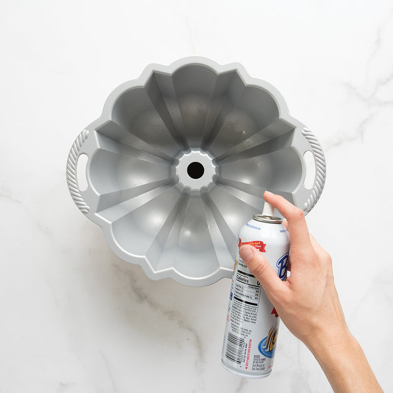 Hand holding Nordic Ware | Baker's Joy Nonstick Baking Spray can, ideal for flawless baking without sticky residue, from Athens Cooks kitchen store.