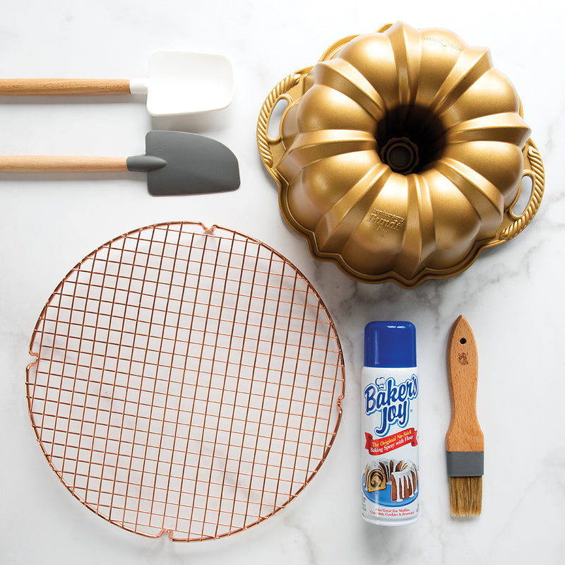 Nordic Ware | Baker's Joy Nonstick Baking Spray with baking utensils and a bundt cake pan on a marble surface, ideal for perfect baking results.
