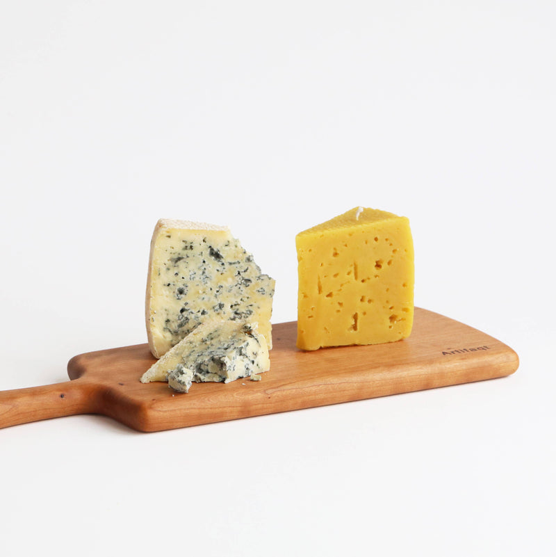 Artifaqt - Blue Cheese Beeswax Candle molded from Birchrun Hills Blue Cheese, displayed on a wooden board, showcasing its unique design and artisanal craftsmanship.