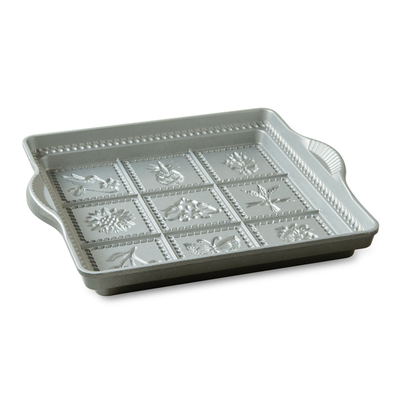 Nordic Ware | English Shortbread Pan featuring a white square tray with handles, designed to create nine flower and fruit patterns for baking delightful shortbread.