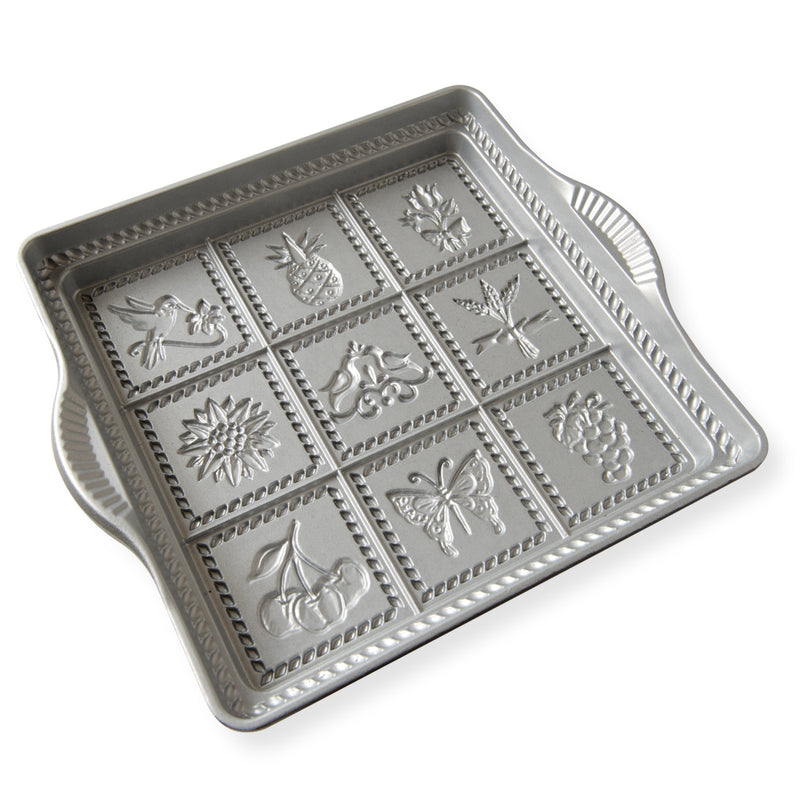 Nordic Ware | English Shortbread Pan, a square silver tray featuring intricate flower and fruit designs for creating delicate shortbread cookies.
