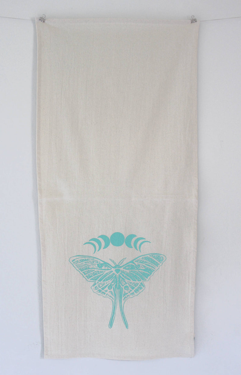 Hearth and Harrow - Organic Cotton Luna Moth Tea Towel featuring a screen-printed moth and moon phases design, displayed against a white wall. Eco-friendly and handcrafted.
