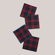 Atelier Saucier | Jubilee Plaid Cocktail Napkins, Set of 4 featuring red-and-green tartan patterns with varied colored edge bindings, perfect for festive gatherings.