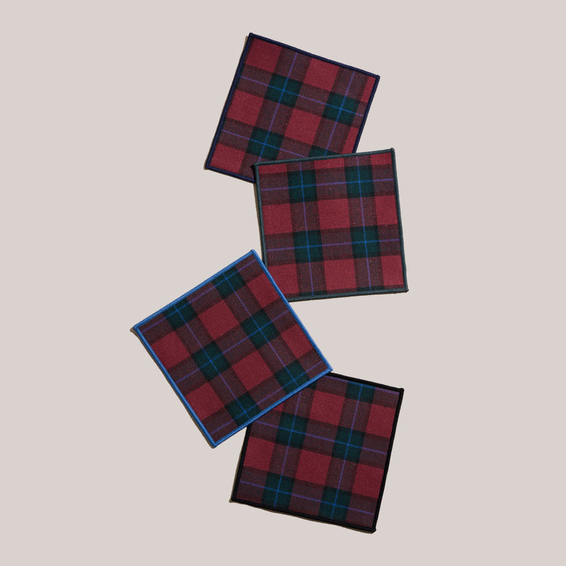 Atelier Saucier | Jubilee Plaid Cocktail Napkins, Set of 4 featuring red-and-green tartan patterns with varied colored edge bindings, perfect for festive gatherings.