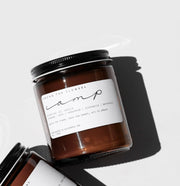 Among the Flowers | Essential Oil + Soy Wax Candle Wilder in amber jar with black lid, showcasing fragrance notes on label, ideal for kitchen ambiance.