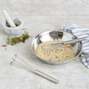 RSVP | Silicone Ball Whisk in a mixing bowl, showcased with a mortar and pestle, ideal for efficient mixing without scratching cookware.