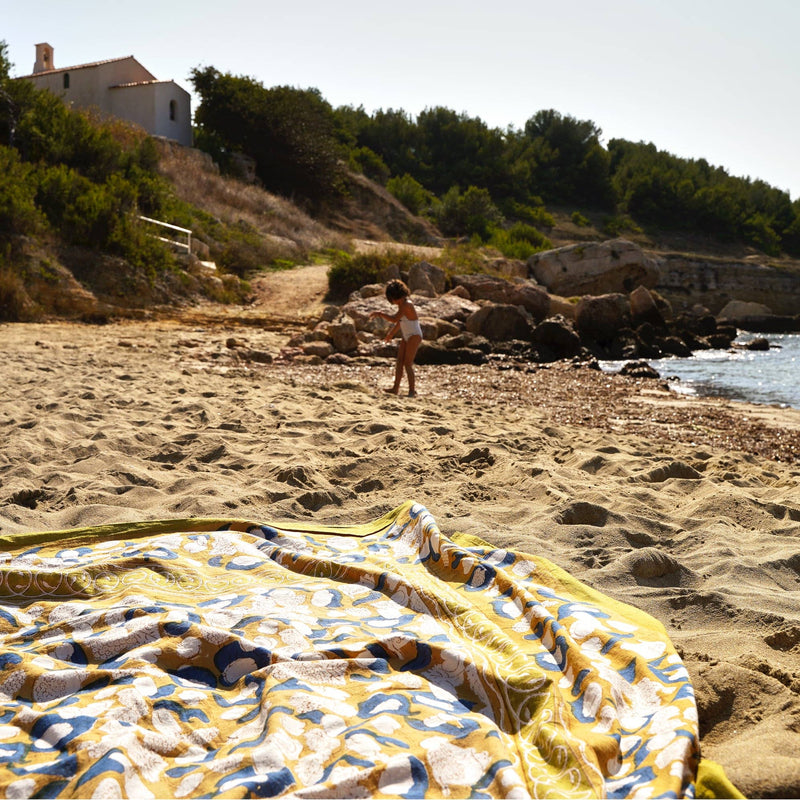 Couleur Nature - Forest Harvest Mustard & Blue tablecloth on a sunlit beach, showcasing a Provençal-inspired pattern, hand-printed and ideal for elegant, relaxed dining.