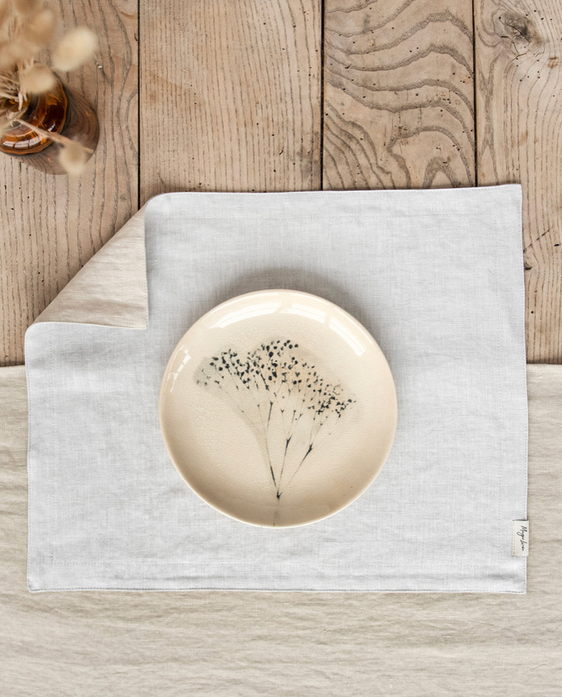 MagicLinen - Double Layer Linen Placemat Set of 2: Grey blue, displayed on a table with a plate featuring a floral design, highlighting its elegance and softness.