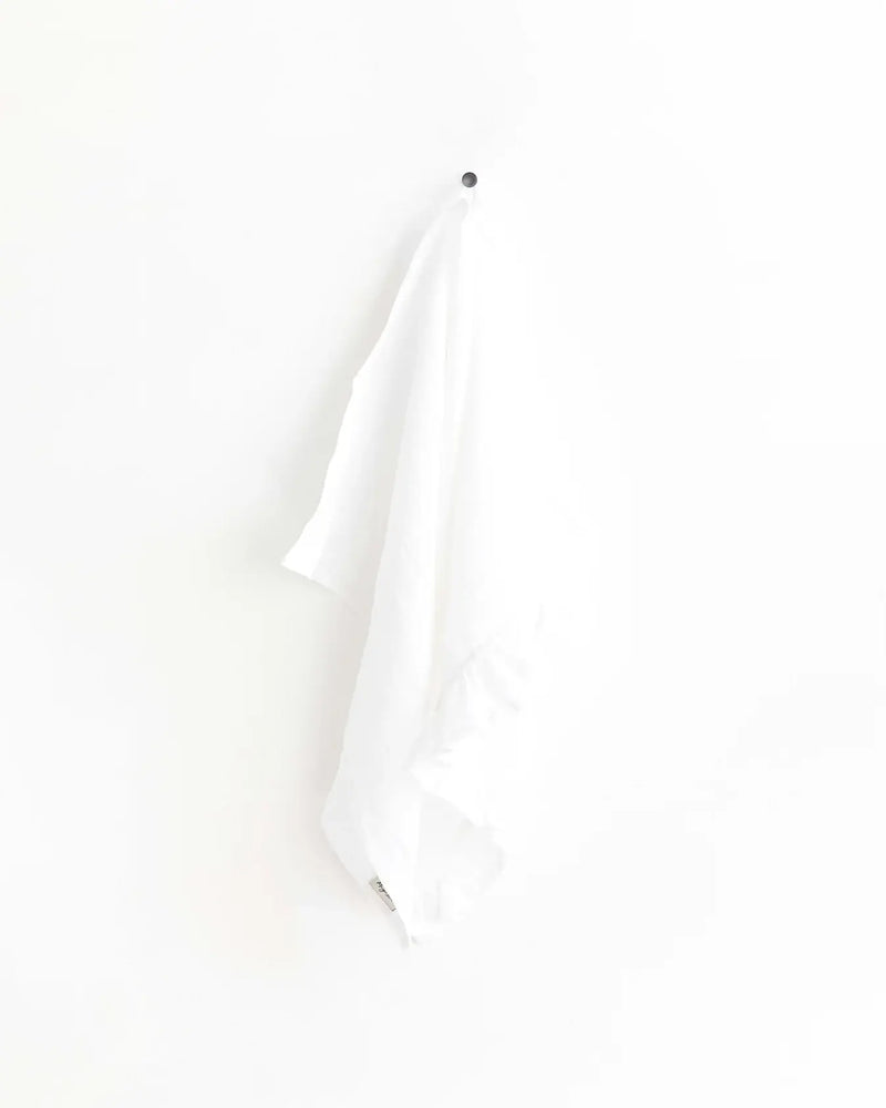 MagicLinen - Ruffle trim tea towel hangs on a hook, showcasing its elegant design and practicality for kitchen use.