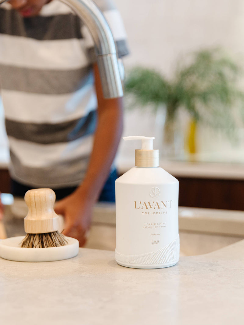 L'AVANT Collective - Fresh Linen High Performing Dish Soap and brush, featuring a reusable white glass bottle with wooden handle, ideal for modern kitchens.
