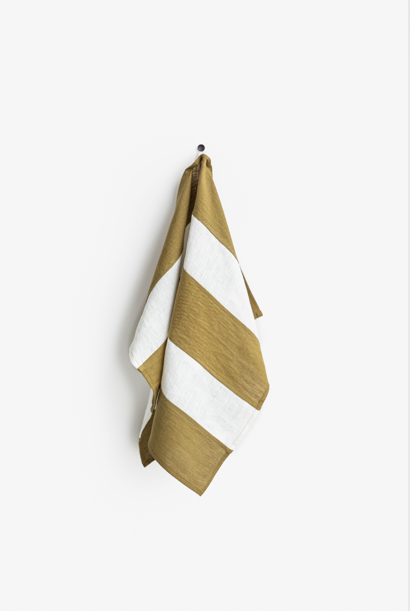 Striped linen tea towel on a hook, showcasing its practical hanging loop. Part of a zero-waste collection, crafted for durability and absorbency.