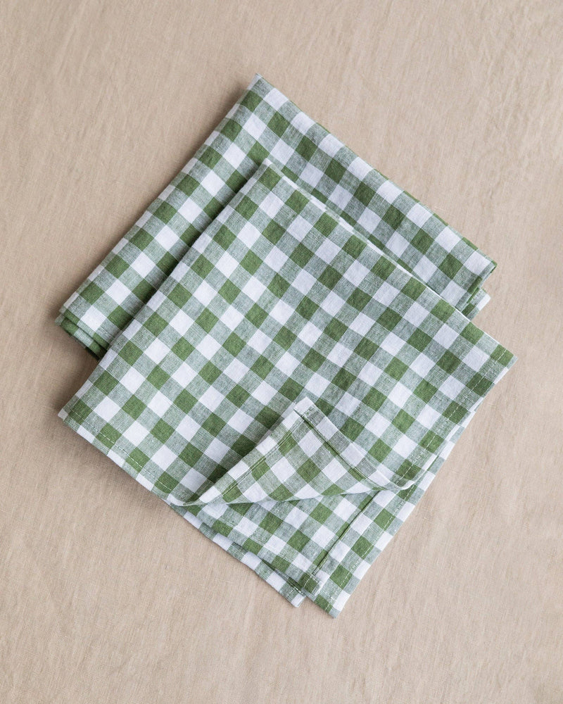 MagicLinen - Forest green gingham linen napkin set of 2, folded, showcasing a checkered pattern, perfect for enhancing any dining table setting.