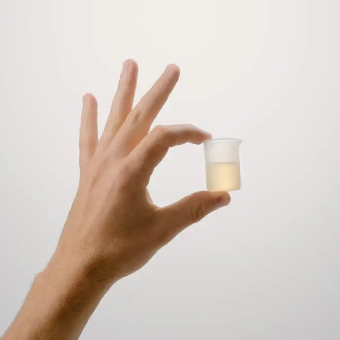 Dirty Labs Reusable Silicone Measuring Beaker — silicone beaker held between fingers