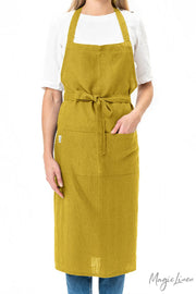 Woman wearing MagicLinen - Charcoal Grey Linen Bib Apron with Pockets, ideal for cooking and gardening, showcasing its stylish, unisex design and functionality.