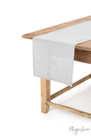 MagicLinen linen table runner on a wooden table, showcasing a decorative and protective addition for dining, available in various colors and sizes, including 16 x 79 inches.