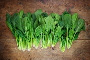 Bentley Seed Co. - Spinach-Bloomsdale Savory 1820: Fresh spinach bunches on wooden surface, ideal for salads or smoothies, grown from heirloom seeds.