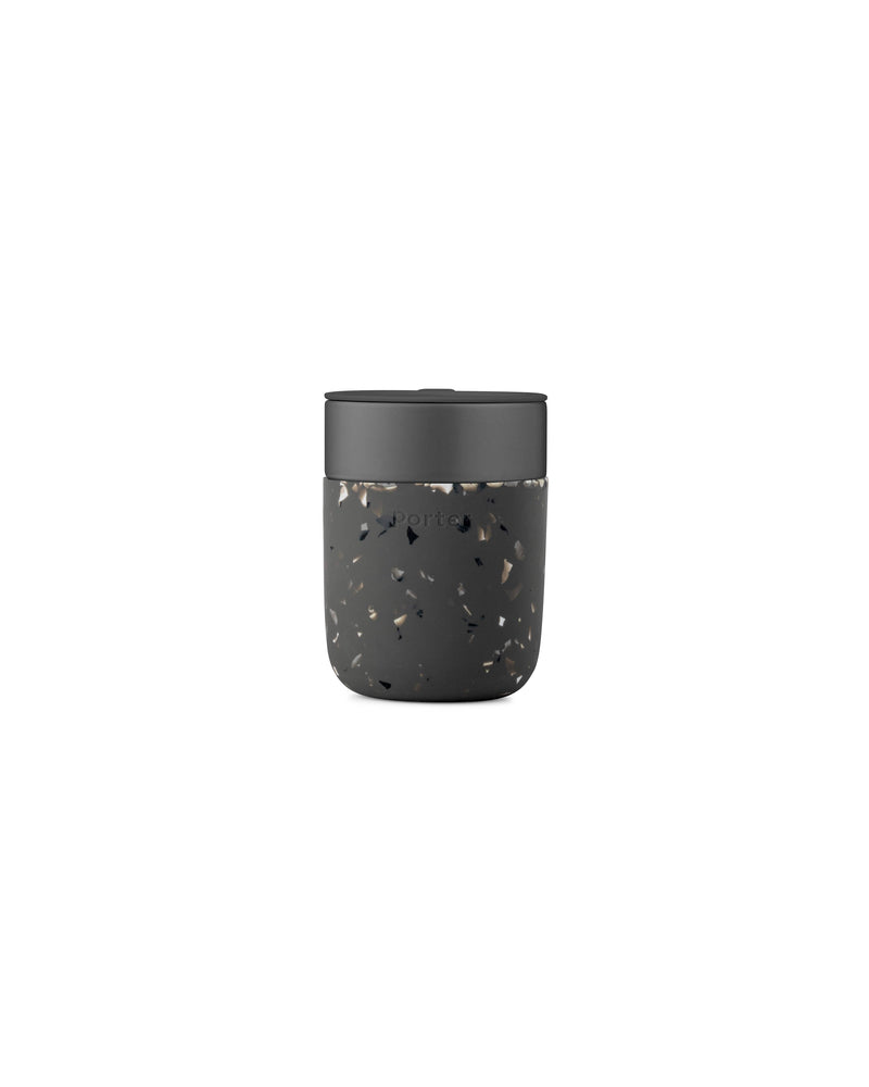Reusable Ceramic Mug: Terrazzo Charcoal, 16 oz, featuring a black lid and speckled silicone sleeve for grip. Ideal for eco-friendly, on-the-go beverage enjoyment.