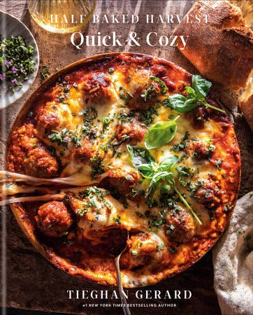 Cookbook cover for Half Baked Harvest Quick & Cozy by Tieghan Gerard, featuring a cheesy meatball skillet dish with herbs, epitomizing quick, comforting recipes.