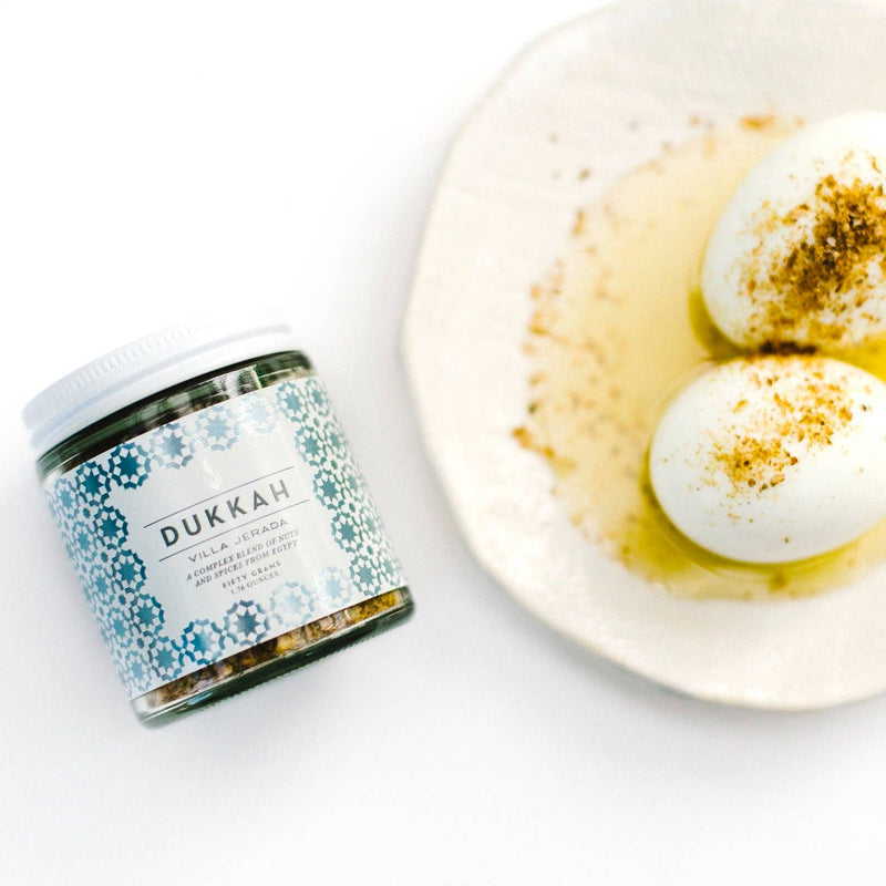 Villa Jerada - Dukkah - 50g jar beside hard-boiled eggs in olive oil, showcasing its use as a versatile Egyptian nut-and-spice blend.