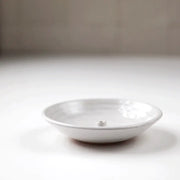 Gravesco Pottery Incense Burner, a minimalist white ceramic dish, features a central peg for incense sticks, designed to catch ash efficiently.