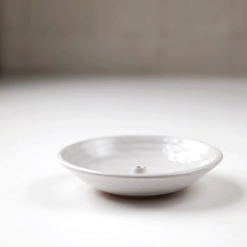Gravesco Pottery Incense Burner, a minimalist white ceramic dish, features a central peg for incense sticks, designed to catch ash efficiently.