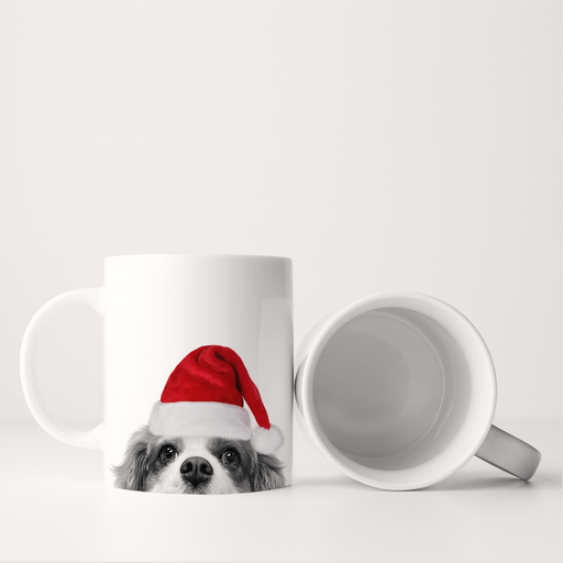 Perkie Prints - Santa Hat Cavalier King Charles 1 Mug featuring a Cavalier King Charles Spaniel in a Santa hat, standing and lying on a white surface.