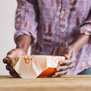 Bee's Wrap - Large 3 Pack Wraps held over a bowl, showcasing the reusable beeswax wrap's signature Honeycomb design, perfect for preserving kitchen items sustainably.