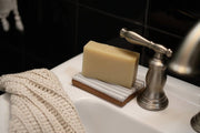 Gravesco Pottery - Soap Dish, handmade in white ceramic, holds a natural soap bar on a sink with metal faucet, highlighting its unique, handcrafted design.