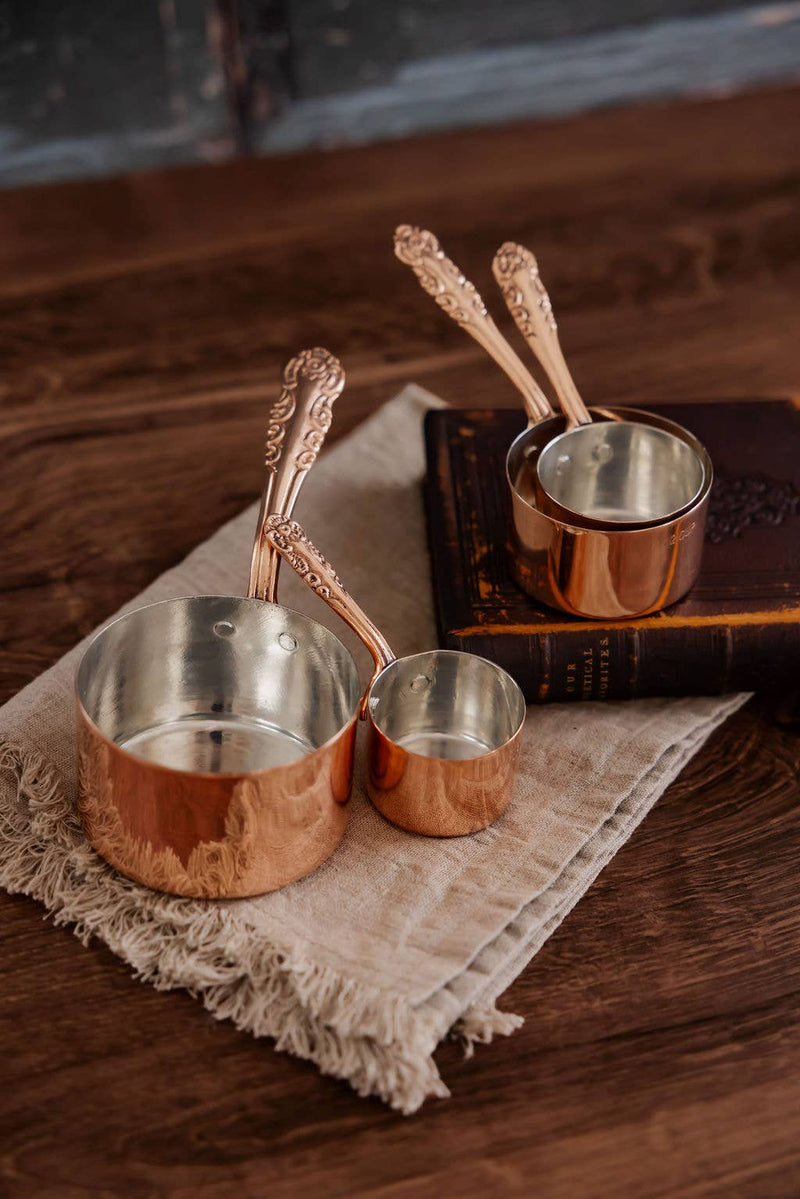 Coppermill Kitchen LLC - Vintage Inspired Measuring Cups with embossed handles, silver tin lining, artistically arranged on linen, embodying charm and functionality.