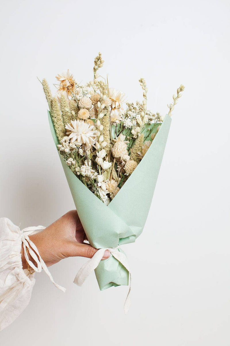 Idlewild Floral Co. - Sage Small Field Bouquet, featuring dried cream and pale yellow flowers wrapped in green paper with a white ribbon, perfect for vases.
