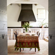 Couleur Nature - Noel Red & Green tablecloth adorns a rustic dining table, beneath a vase of fresh flowers and red wine glasses, evoking festive elegance.