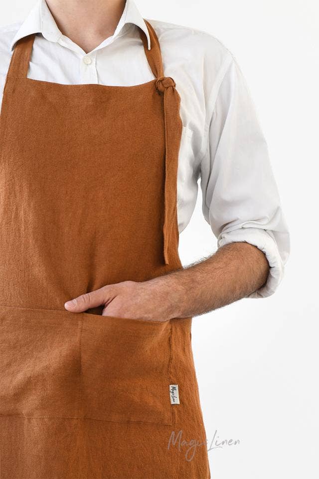 Person wearing a MagicLinen men's linen bib apron with a front pocket and adjustable straps, ideal for grilling and cooking.