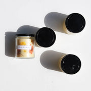 Among the Flowers | Essential Oil Candle, Homeward: Four small glass-jar candles with creamy-white wax and dried petals, showcasing a natural, low-smoke blend of essential oils.