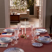 Dining table featuring Royal Copenhagen's Blue Fluted Plain Plate, 23cm deep, elegantly set with patterned china, crystal-cut glassware, and silver flatware, under candlelight.