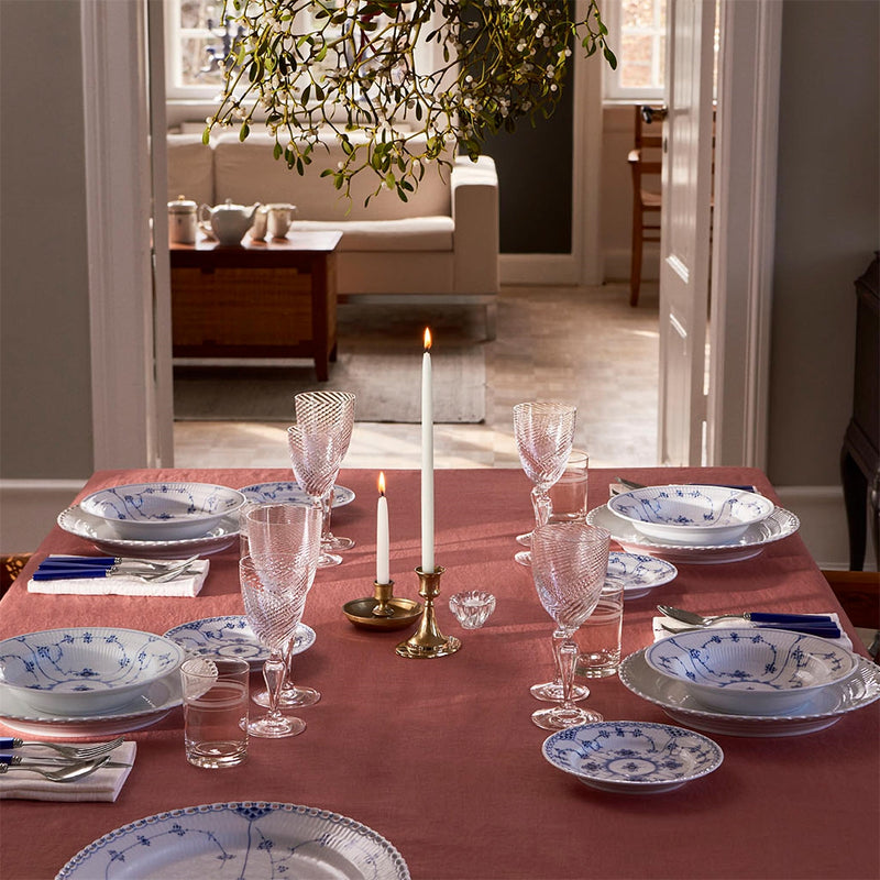 Dining table featuring Royal Copenhagen's Blue Fluted Plain Plate, 23cm deep, elegantly set with patterned china, crystal-cut glassware, and silver flatware, under candlelight.