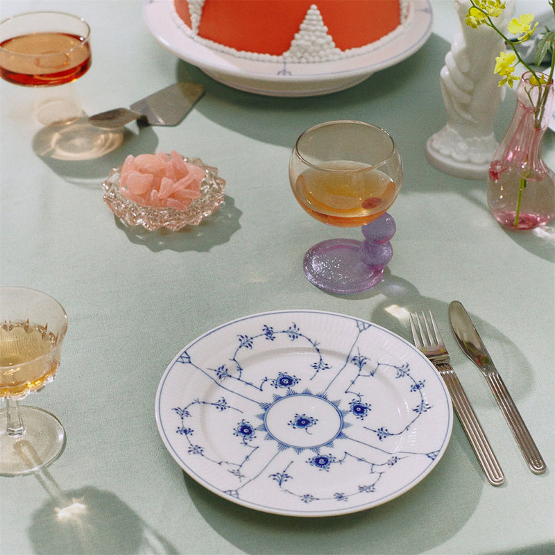 Royal Copenhagen | Blue Fluted Plain Plate, 22cm, featuring hand-painted blue floral motifs, elegantly set with stemmed glasses and a cake on a mint-green tablecloth.