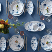 Royal Copenhagen | Blue Fluted Hl Plate, 27cm, elegantly set on a blue tablecloth with vintage flatware and glasses, highlighting delicate floral motifs and craftsmanship.