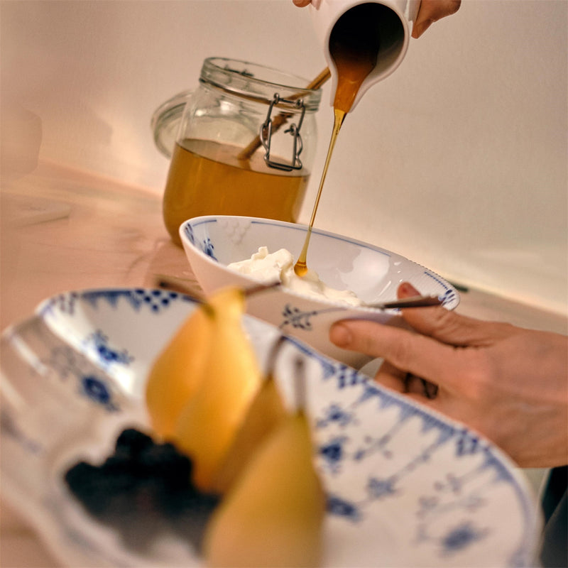 Royal Copenhagen | Blue Elements Bowl 78cl filled with yogurt, being drizzled with honey, alongside poached pears and berries, showcasing elegance and playful design.